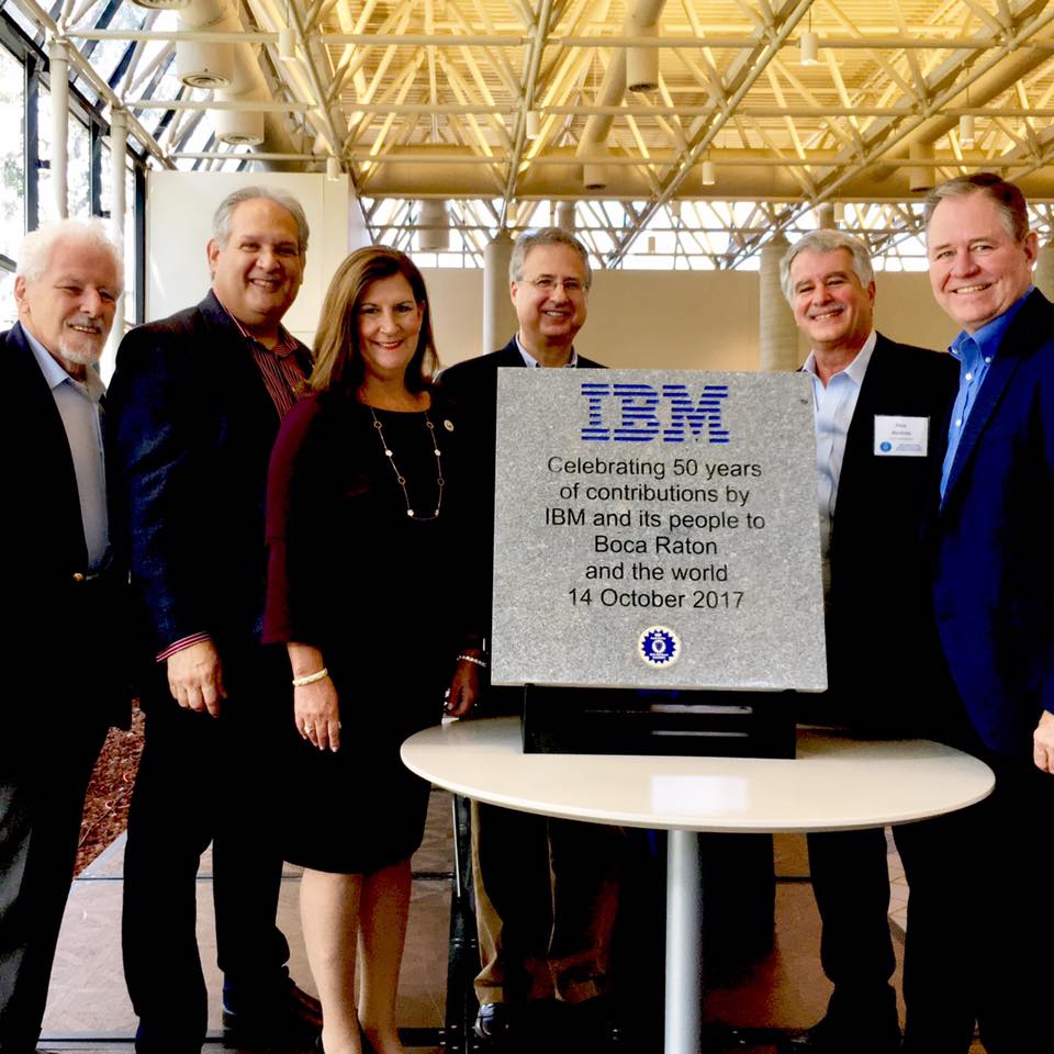 Group of business people standing behind an IBM placard